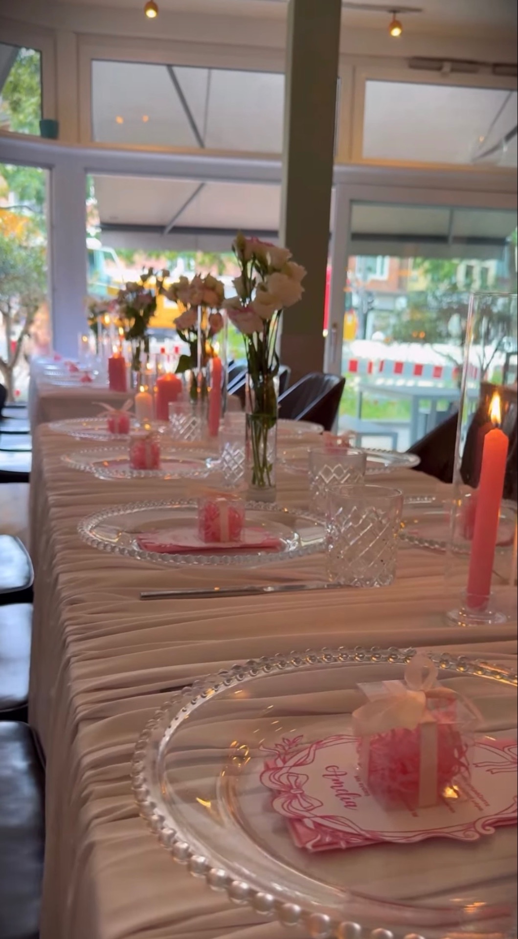 Lange Tauftafel mit gefalteter weißer Tischdecke, rosa Servietten, Kerzen in Koralle und weißen Blumen in hohen Vasen